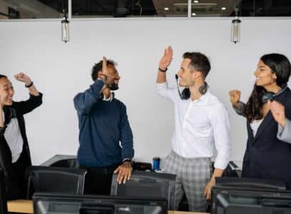 A team of employees high fiving each other while looking happy