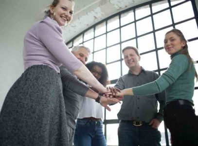 Employees standing in a circle with their hand out on top of each other